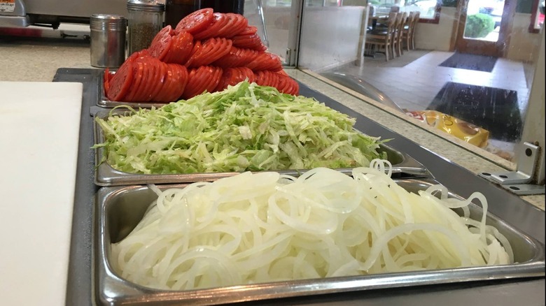 Toppings in metal bins behind glass