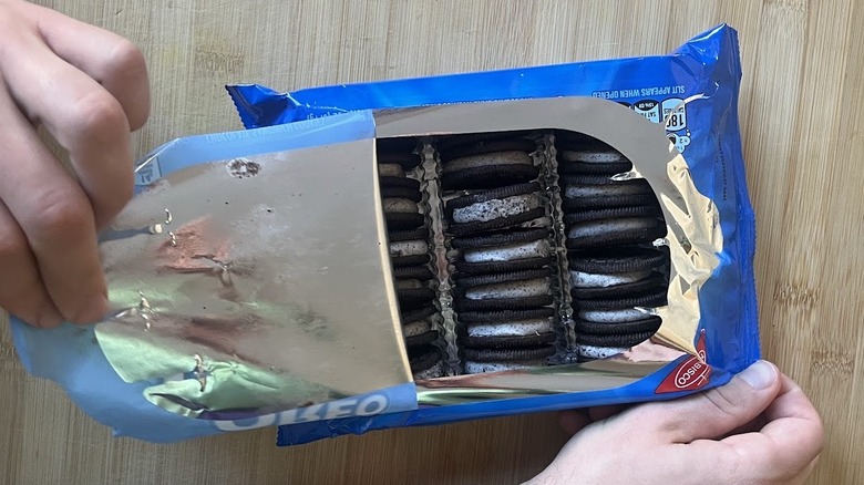 A hand peels open a package of Loaded Oreos.