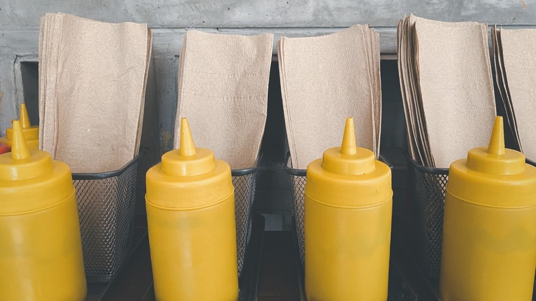 Four yellow squeeze bottles of mustard lined up