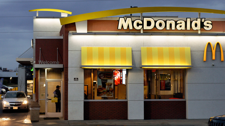 The exterior of a McDonald's location with a car in the bottom left at the drive-thru window