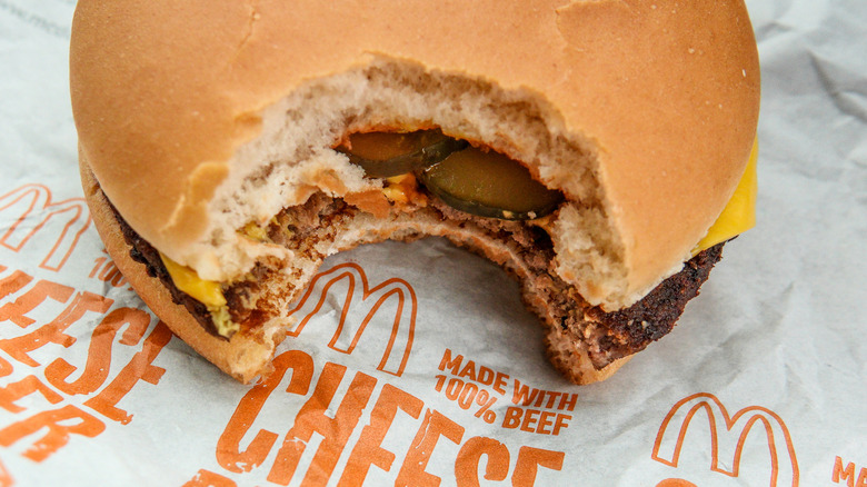 A top-down view of a bitten McDonald's cheeseburger on a McDonald's wrapper