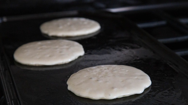 Raw pancakes on griddle