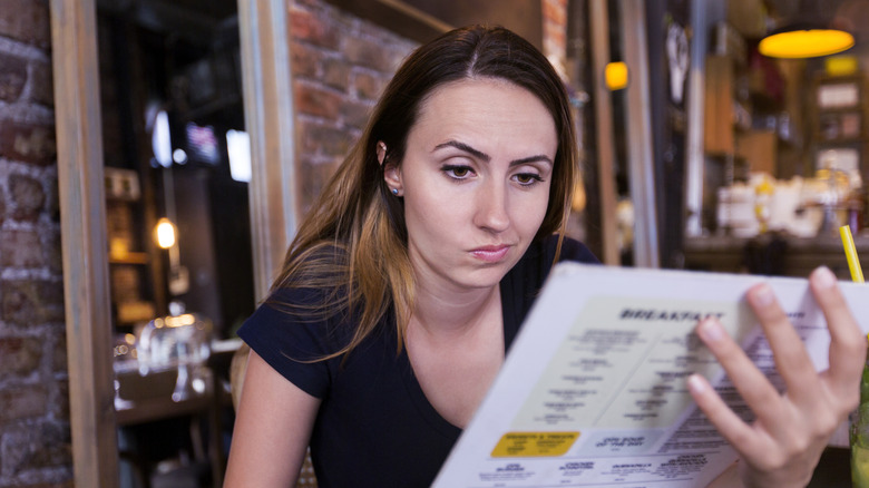 Restaurant patron looking suspiciously at restaurant menu