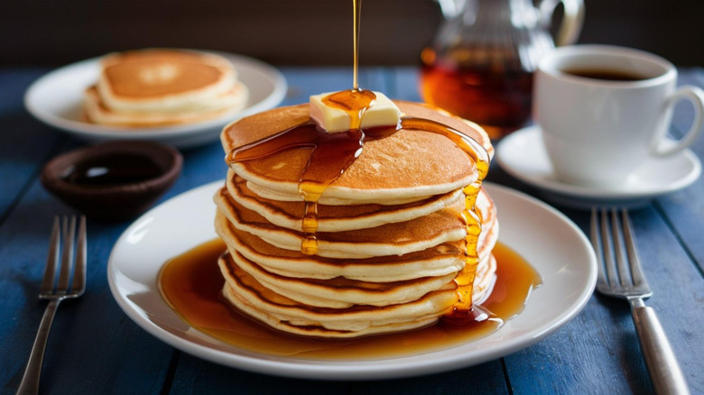 Syrup poured over stacked pancakes with butter