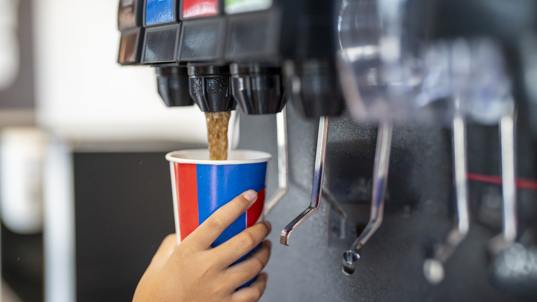 Person fills up cup at soda machine