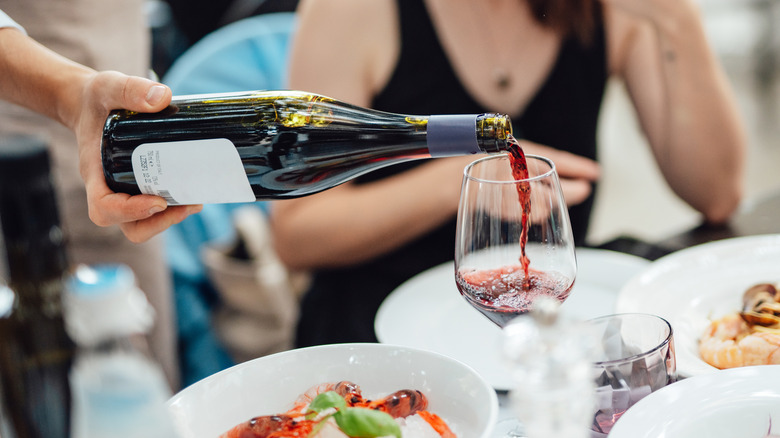 Server pours red wine into glass at restaurant