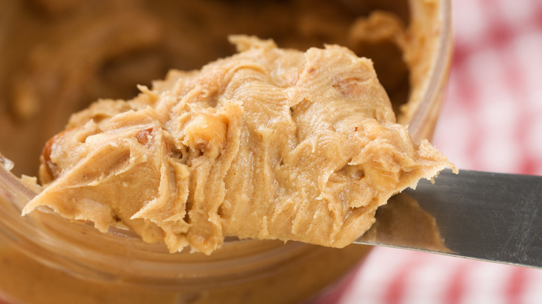 Peanut butter scooped out of a jar on a knife