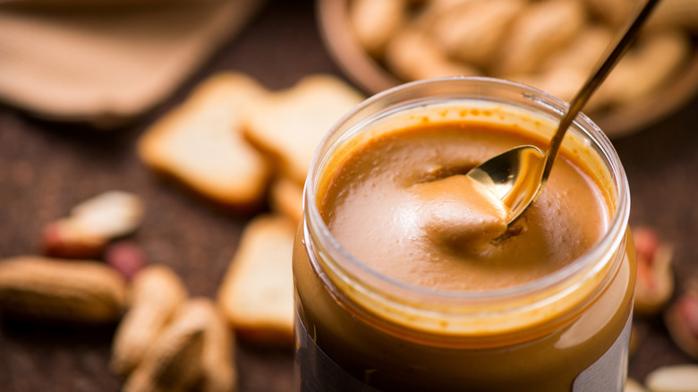 Open jar of peanut butter with a spoon in it