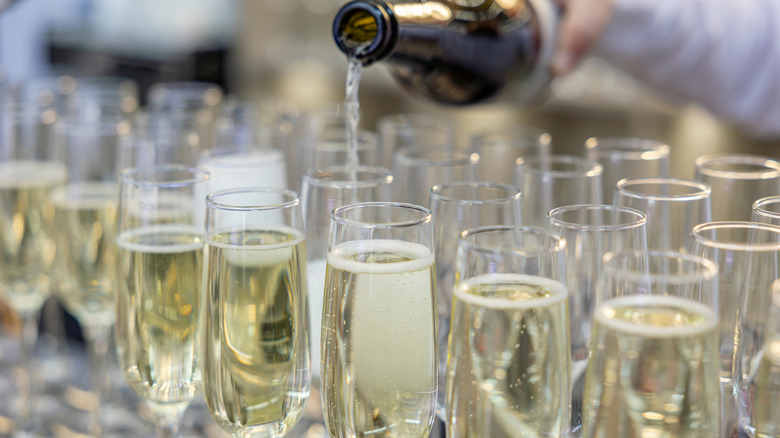 A server pouring champagne into flutes