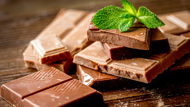 Chocolate bars and mint leaves on wooden table