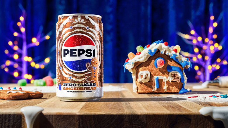 A Pepsi Zero Sugar Gingerbread Mini Can stands next to a mini gingerbread house