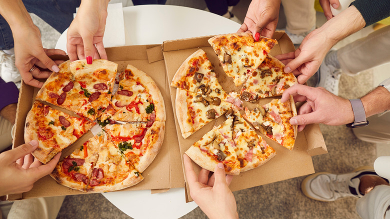 Hands grabbing slices of pizza