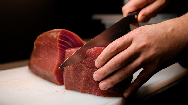 Hands cutting a tuna filet