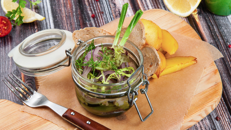 Pickled herring in an open jar with fork and bread