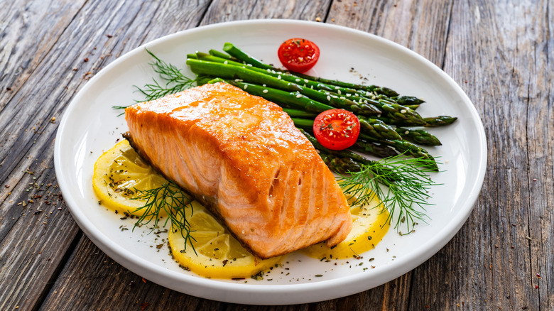 Cooked salmon on plate with asparagus and lemon slices