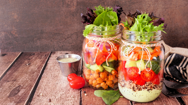 mason jar meals with dressing, quinoa, and veggies