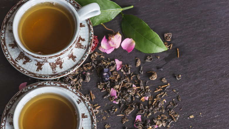 Two cups of tea with tea leaves and rose petals