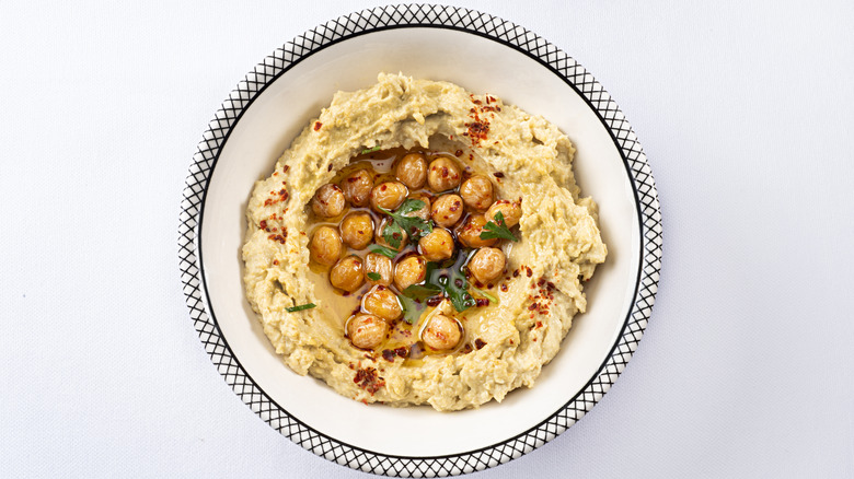 hummus with oil, red spice, whole chickpeas, and green herbs