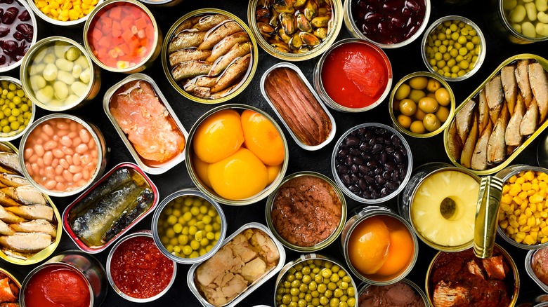 A variety of canned seafood and produce on a black table