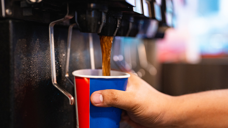 hand filling paper cup at soda fountain