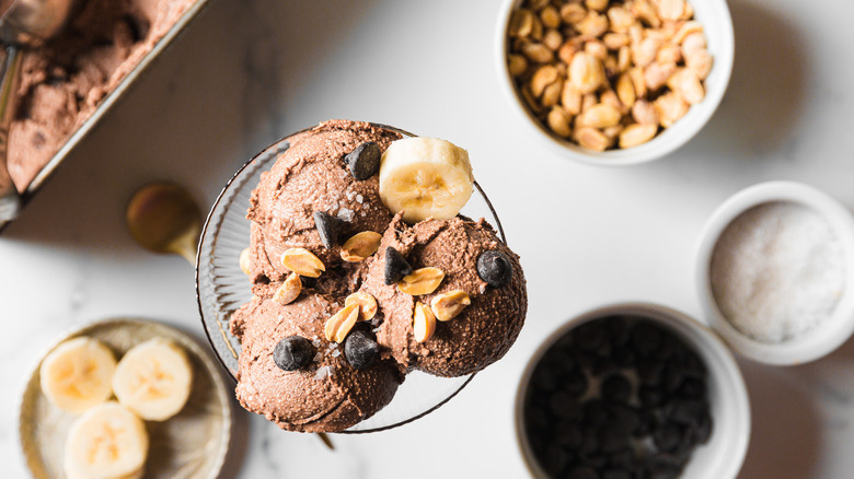 Chocolate ice cream with big container and peanuts in background