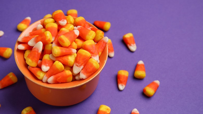 Orange bowl of candy corn on purple background