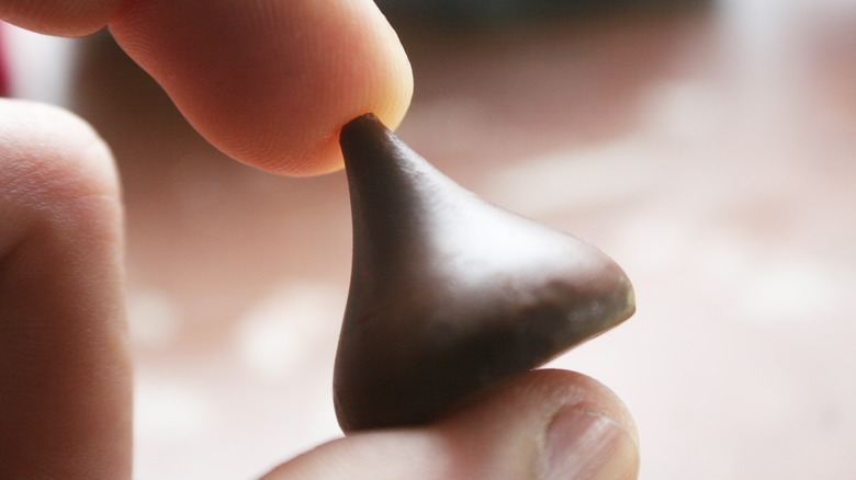 Fingers holding a Hershey's kiss chocolate