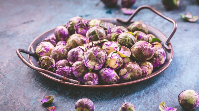 Metal serving platter full of purple Brussels sprouts