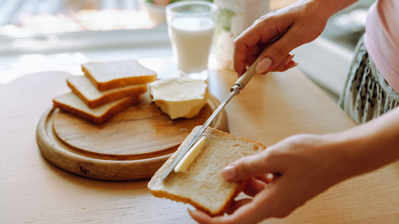 A woman spreading butter on a piece of toast