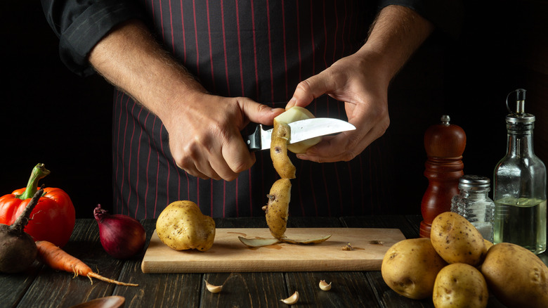 A man peels potatoes with a knife