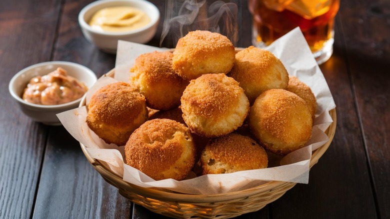 a bowl of hush puppies with drink and sauces