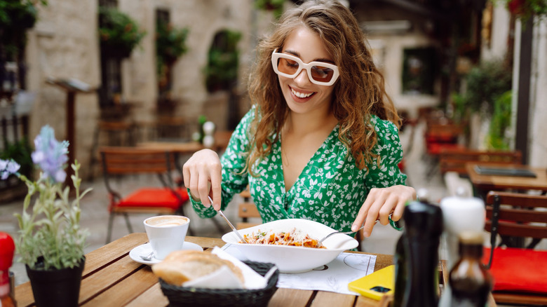 Person smiles while eating Italian food outside