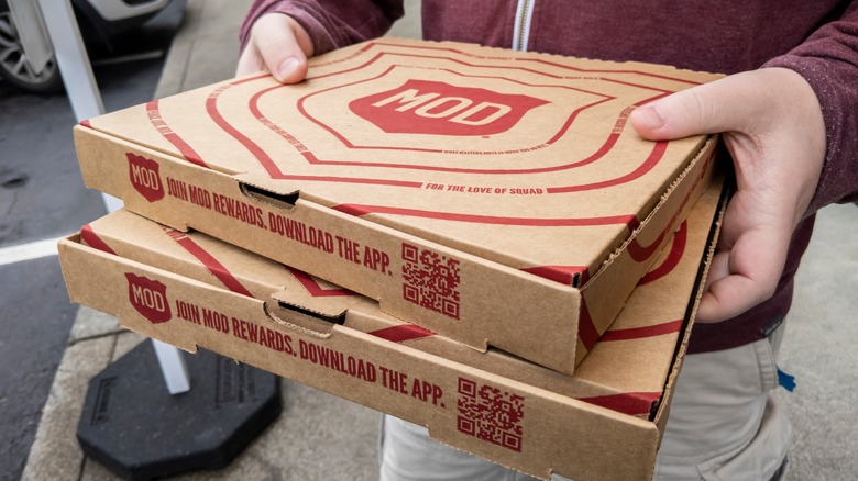 Hands holding MOD Pizza boxes