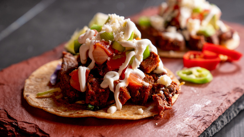 Steak taco covered with peppers and sour cream