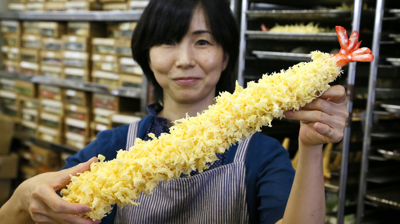 An employee at a sampuru factory holding a giant piece of fake tempura