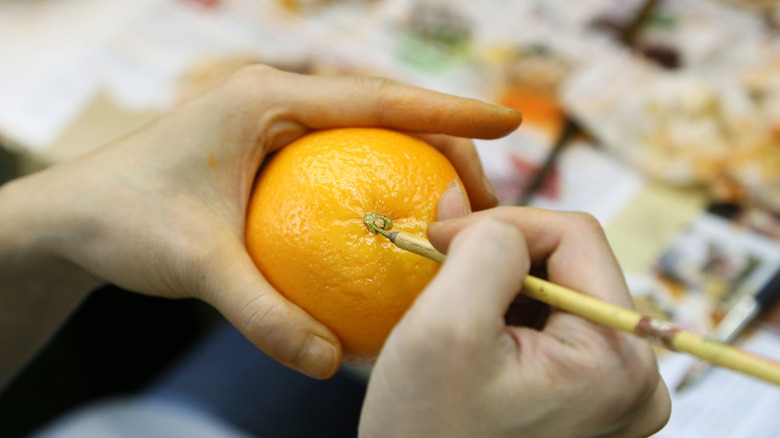 An artisan painting a sampurui orange.