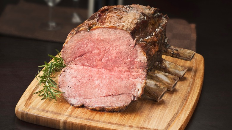 A prime rib roast laid out on a wooden cutting board.