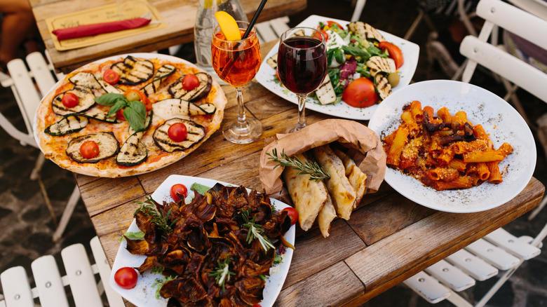 Variety of Italian dishes and drinks on outdoor wodden table