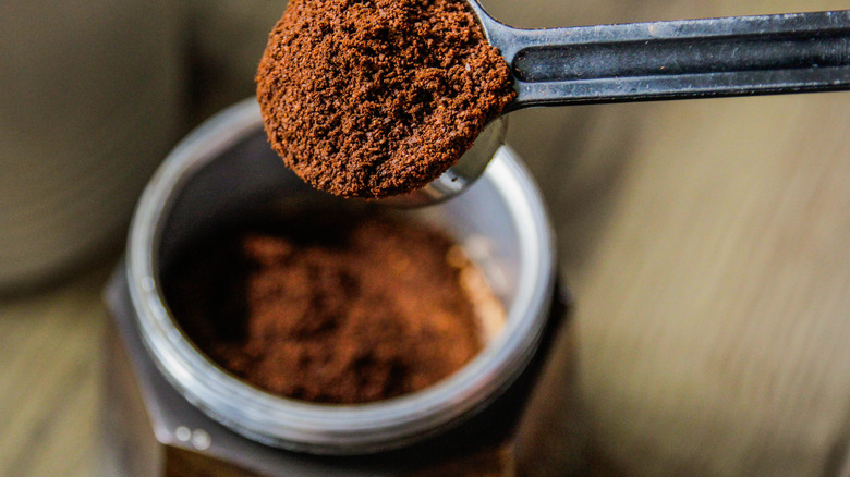 a scoop of espresso powder being taken out of a jar.