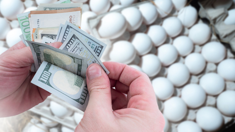 Hands handling cash over egg trays