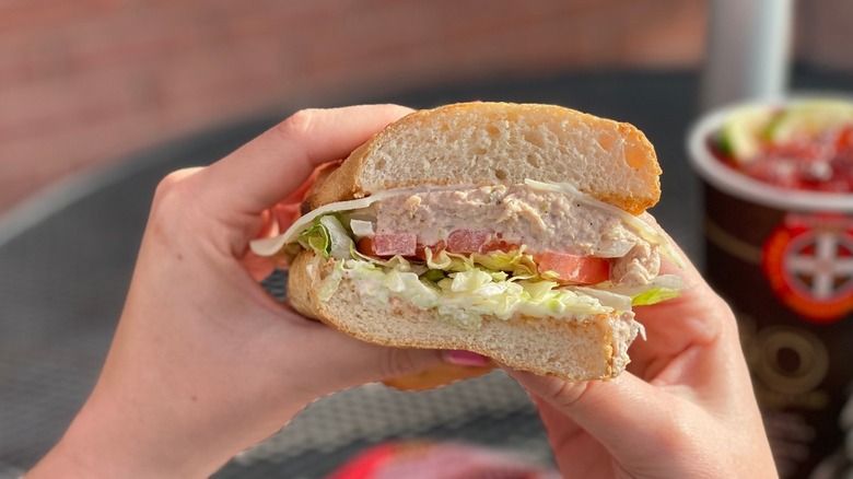 Hand holding Firehouse Subs tuna sandwich