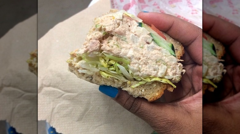 Hand holding up Jimmy John's tuna sandwich