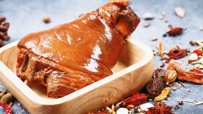 A piece of ready to eat meat sitting in a wood bowl surrounded by potpourri