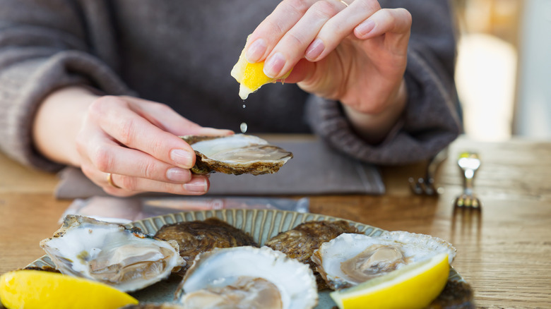 woman squeezing lemon on oyster