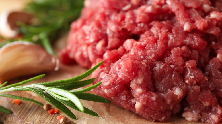 A close up shot of raw ground beef and fresh herbs