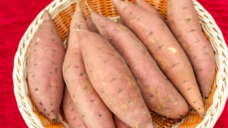 A pile of raw sweet potatoes in basket