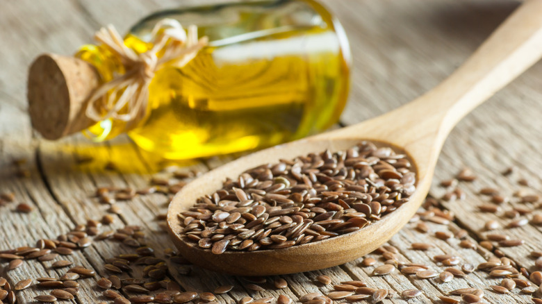 A spoonful of flax seeds with a bottle of flax seed oil