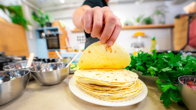 Hand lifting up one tortilla from a stack