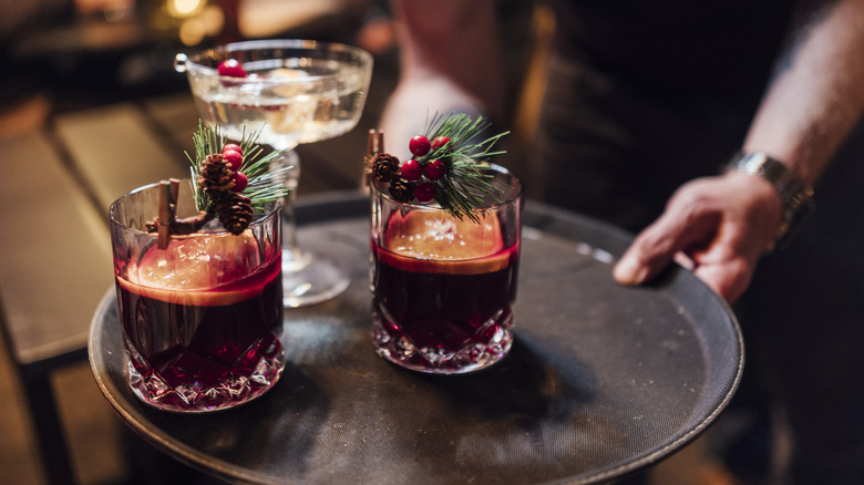 A bar tender handing out three holiday cocktails