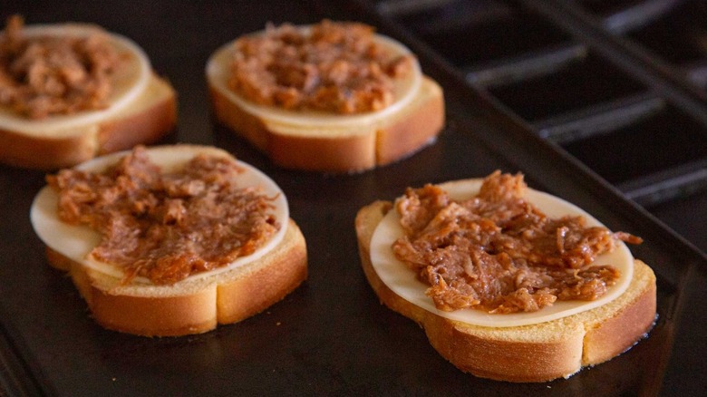 bread topped with sliced cheese and pulled pork